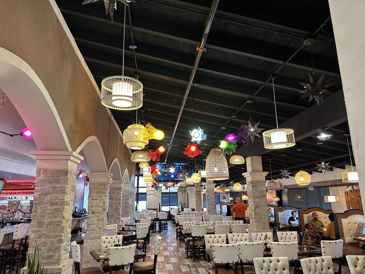 Dining room of a Mexican restaurant with colorful tin star lanterns and stone arches